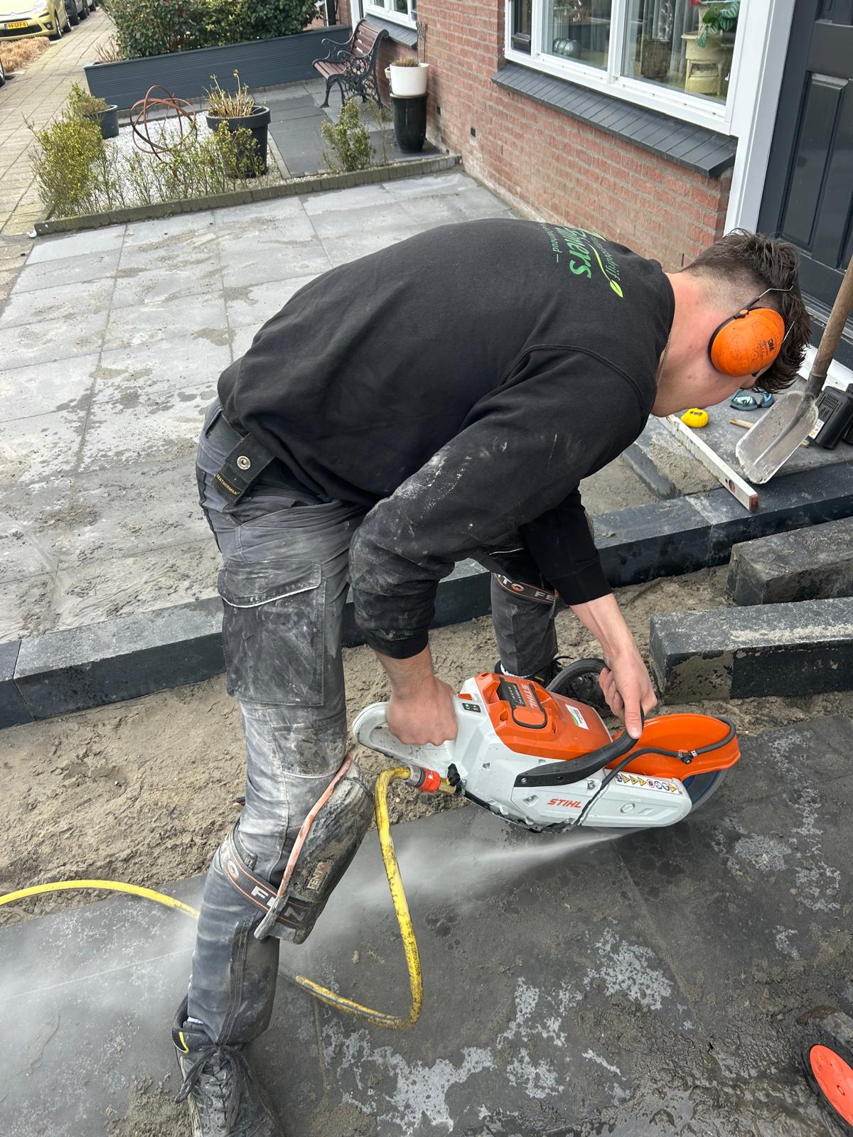 Hovenier zaagt tegel met doorslijpmachine